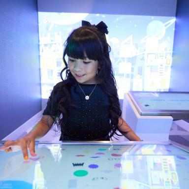 A little girl utilizing the creation station and making a character in Second Story and Beyond